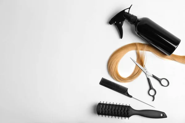 Conjunto de cabeleireiro profissional e fio de cabelo loiro no fundo branco, vista superior — Fotografia de Stock