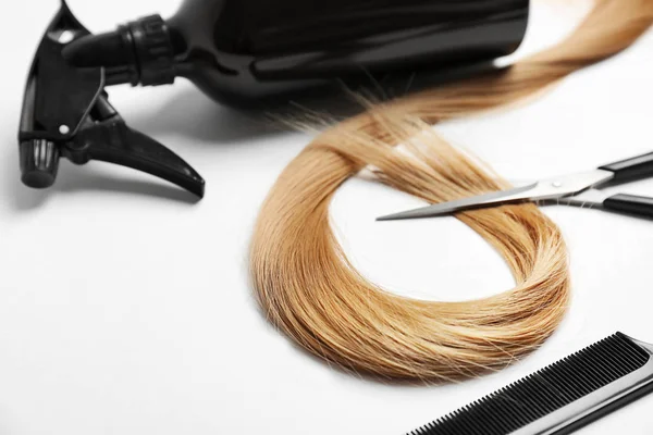 Профессиональный набор парикмахеров и прядь светлых волос на белом фоне — стоковое фото