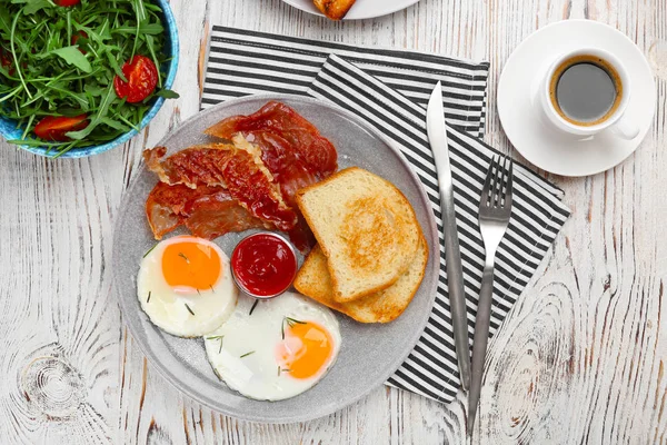 Plaat met gebakken eieren, bacon, toast en saus op houten achtergrond — Stockfoto