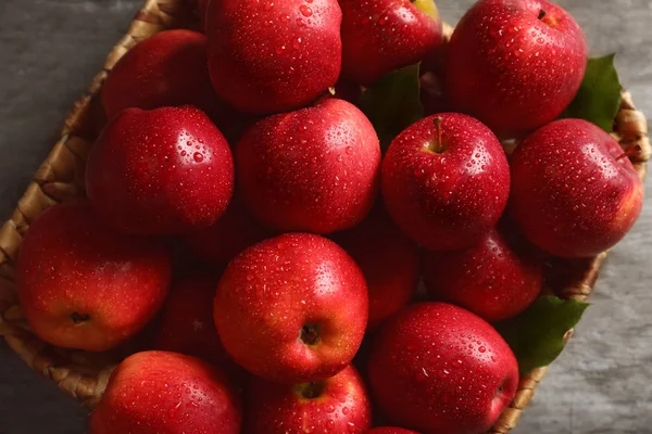 Basket with fresh ripe red apples on wooden table, closeup
