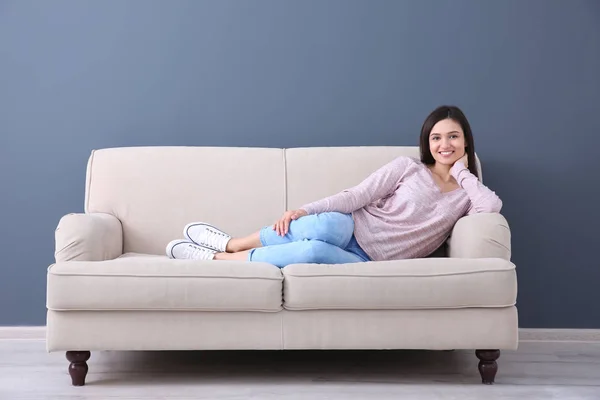 Gelukkig jonge vrouw liggend op de Bank, binnenshuis — Stockfoto