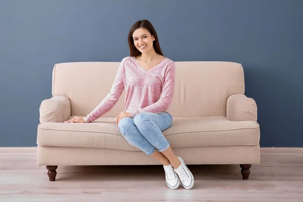 Красива молода жінка сидить на дивані, в приміщенні — стокове фото