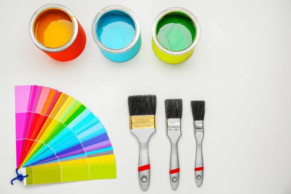 Paint cans, brushes and color palette samples on light background — Stock Photo, Image