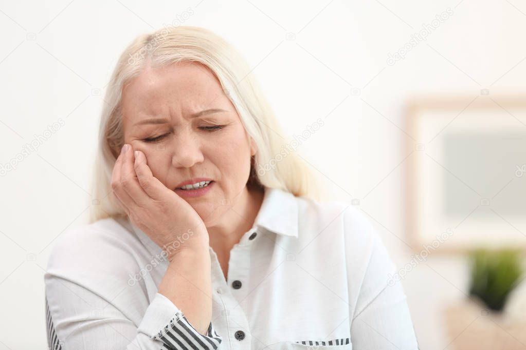 Mature woman suffering from toothache  at home