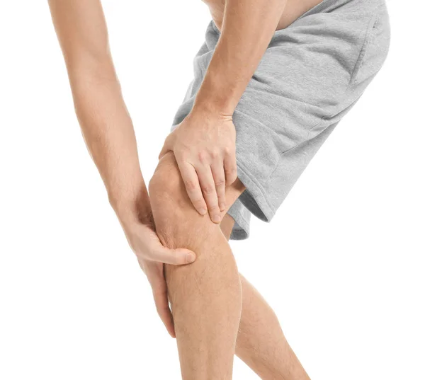 Молодий чоловік, який страждає від болю в коліні на білому тлі — стокове фото