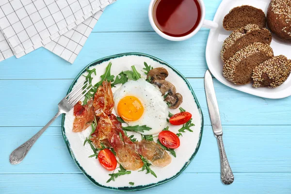 Тарілка зі смаженим яйцем, беконом та овочами на столі — стокове фото