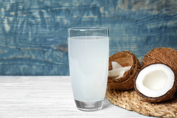 Vaso de agua de coco y nueces frescas sobre mesa de madera — Foto de Stock