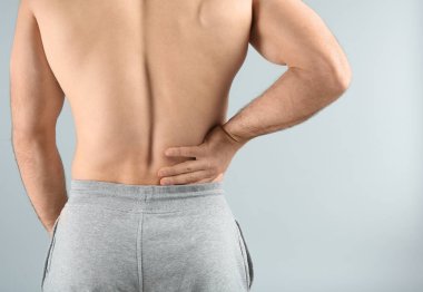 Genç adam açık renkli, closeup üzerinde sırt ağrısı muzdarip