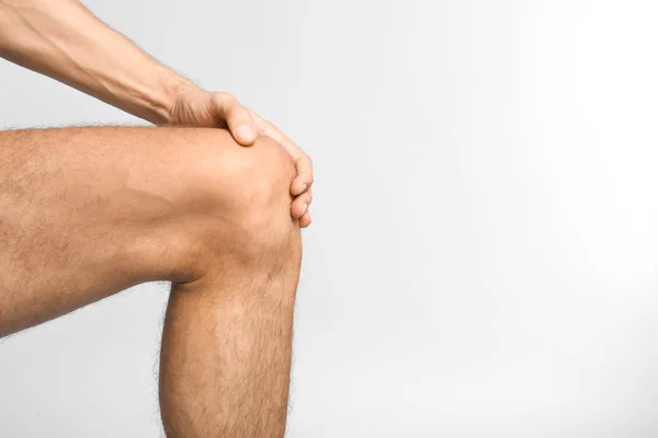 Молодий чоловік, який страждає від болю в коліні на білому тлі — стокове фото