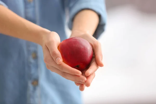 Žena držící zralé červené jablko na rozostřeného pozadí, closeup — Stock fotografie