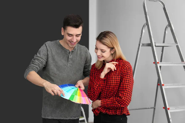 Male decorator and young woman choosing color for walls in empty room — Stock Photo, Image