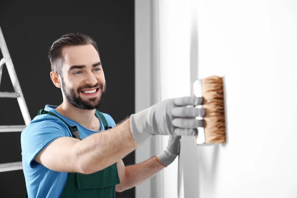 Mannelijke decorateur schilderen muur met borstel binnenshuis — Stockfoto
