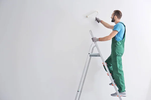 Manliga dekoratör målning väggen med roller i rummet — Stockfoto