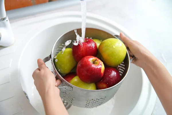 Mujer joven lavando manzanas maduras en la cocina — Foto de Stock