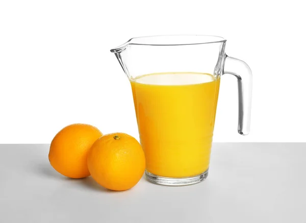 Jarro com suco de laranja e frutas frescas no fundo branco — Fotografia de Stock