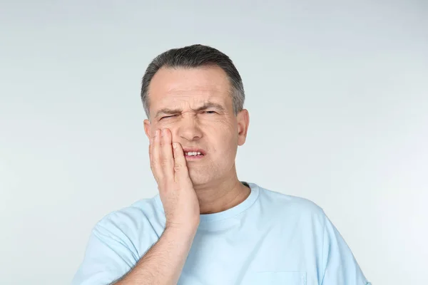 Homme souffrant de maux de dents sur fond clair — Photo