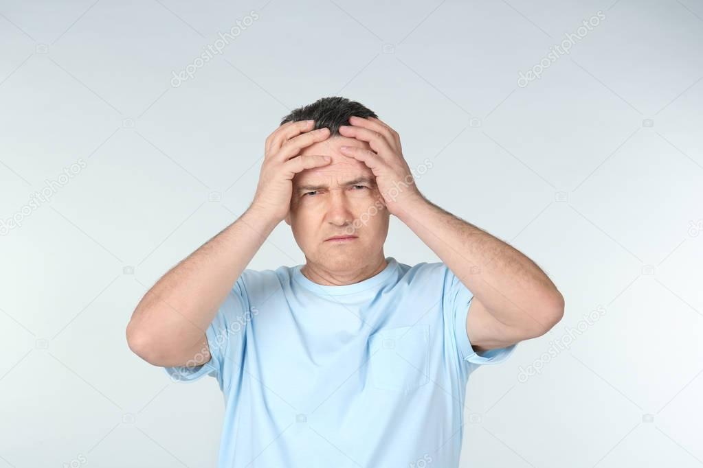 Man suffering from headache on light background