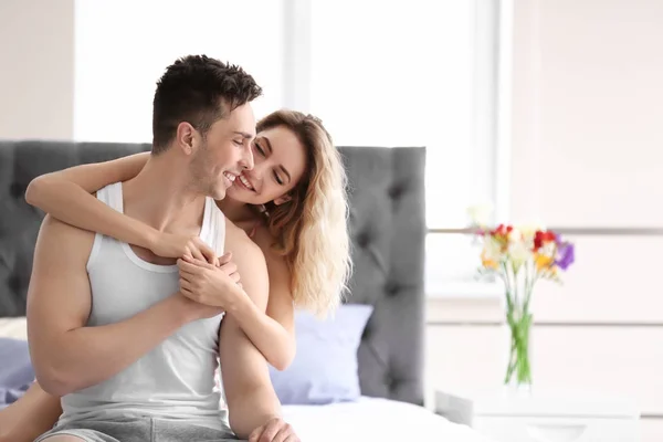 Feliz jovem casal abraçando na cama em casa — Fotografia de Stock