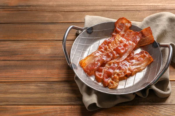 Skålen med stekt bacon på trä bakgrund — Stockfoto