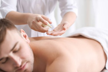 Genç adam spa salonunda masaj yaptırıyor.