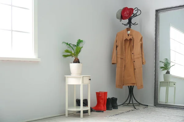 Modern hallway interior with clothes on hanger stand and mirror