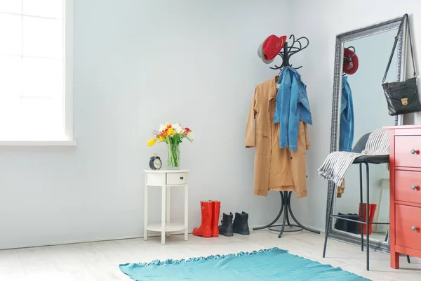 Modern hallway interior with clothes on hanger stand and mirror