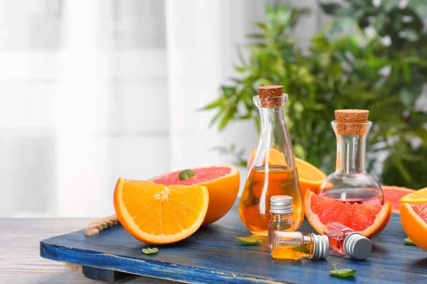 Lahve s esenciálními oleji a čerstvý citrusům na dřevěné desce — Stock fotografie