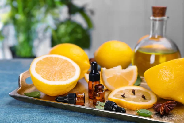 Flaskor med essentiella oljor och färska citroner på bricka — Stockfoto