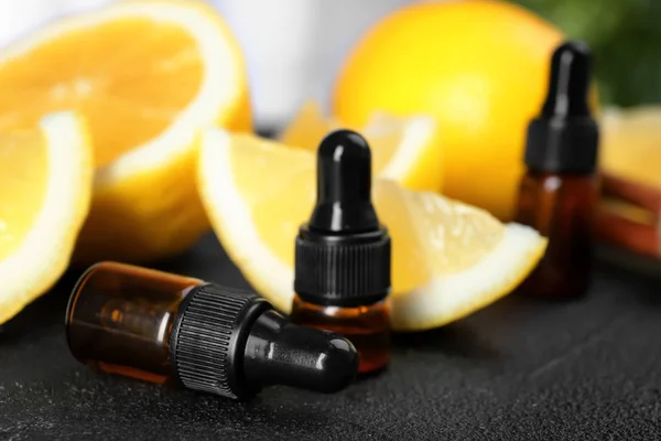 Botellas con aceites esenciales y limones frescos en la mesa, primer plano — Foto de Stock