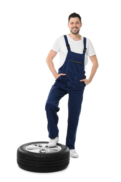 Mecânico masculino em uniforme com pneu de carro no fundo branco — Fotografia de Stock