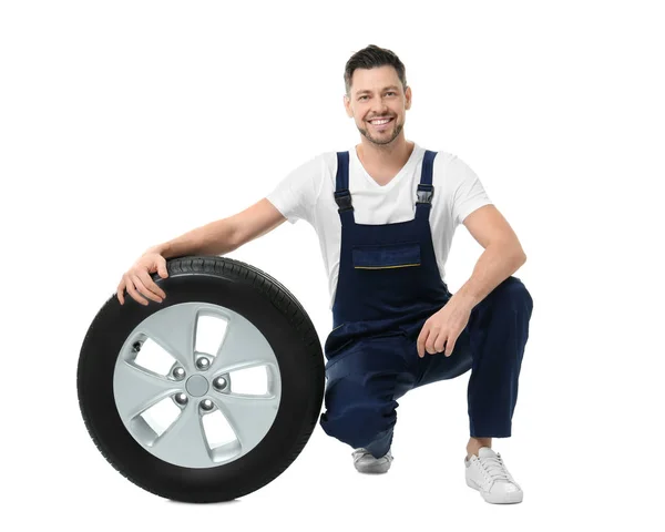 Mecânico masculino em uniforme com pneu de carro no fundo branco — Fotografia de Stock