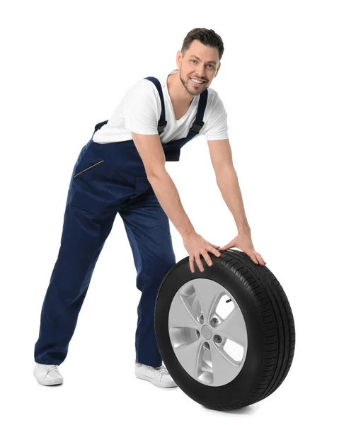 Mecânico masculino em uniforme com pneu de carro no fundo branco — Fotografia de Stock