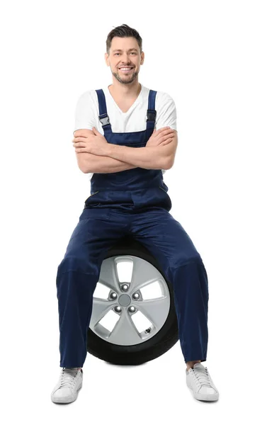 Чоловіча механіка в уніформі з автомобільною шиною на білому тлі — стокове фото