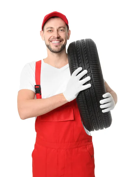 Мужчина-механик в форме с автомобильной шиной на белом фоне — стоковое фото