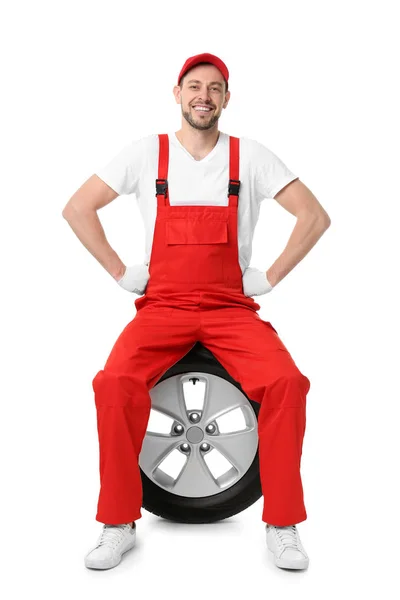 Mécanicien masculin en uniforme avec pneu de voiture sur fond blanc — Photo