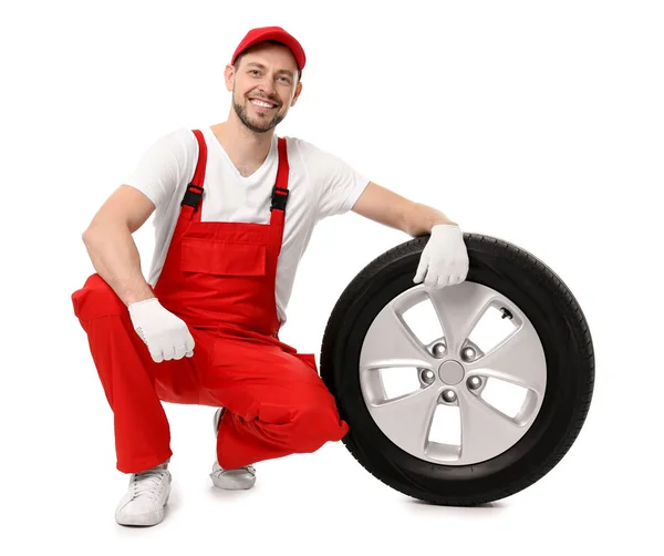 Mecânico masculino em uniforme com pneu de carro no fundo branco — Fotografia de Stock