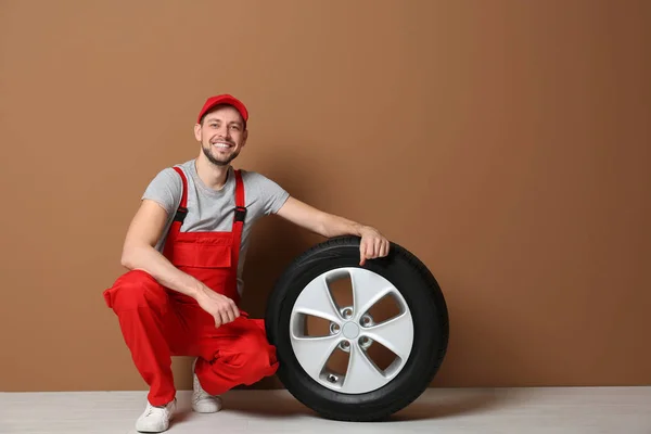 배경에 색 벽에 자동차 타이어와 유니폼에 남성 정비공 — 스톡 사진