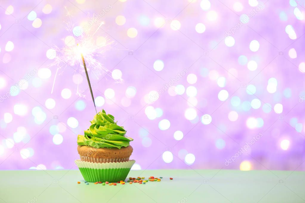 Birthday cupcake with sparkler against blurred lights