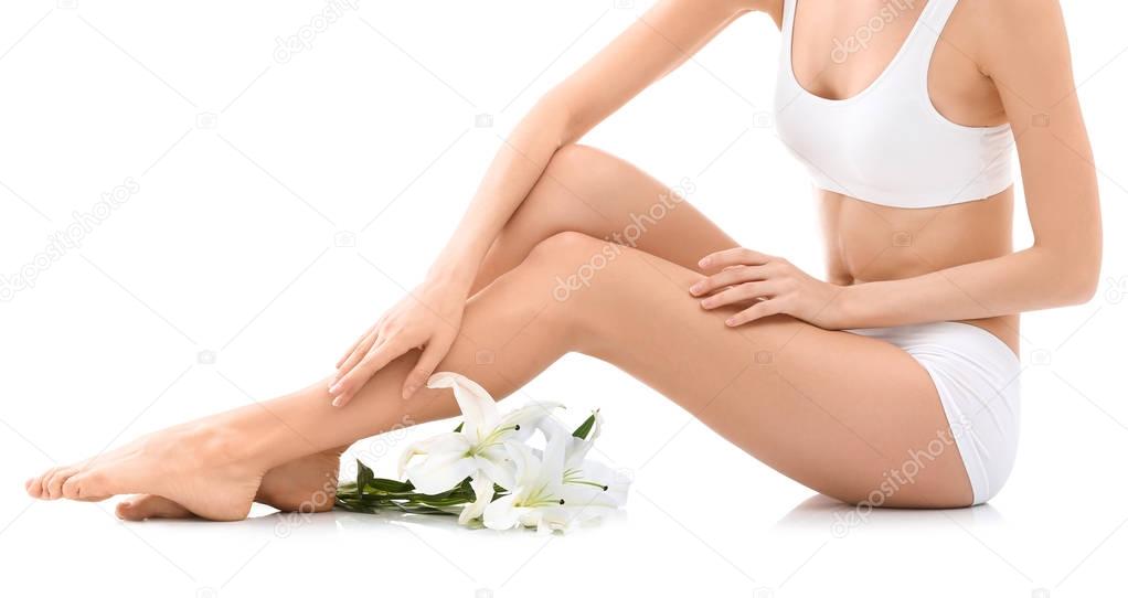 Young woman with beautiful silky body and flowers on white background