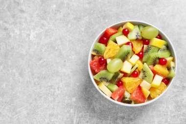 Gri zemin üzerine taze meyve salatası ile kase