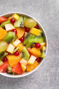 Gri zemin üzerine taze meyve salatası ile kase