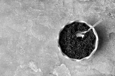 Gri arka plan üzerinde siyah havyar ile metal kase