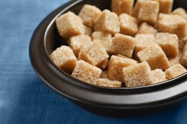 Ahşap arka plan üzerinde kahverengi şeker küpleriyle kase