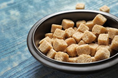 Ahşap arka plan üzerinde kahverengi şeker küpleriyle kase