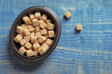 Ahşap arka plan üzerinde kahverengi şeker küpleriyle kase