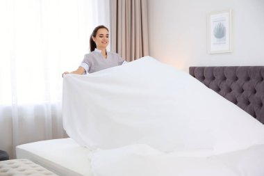 Genç hizmetçi otel odasında yatak yapma