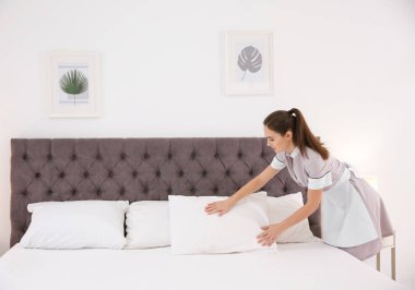 Genç hizmetçi otel odasında yatak yapma