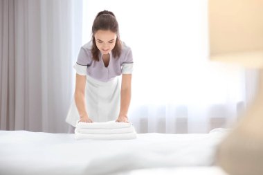 Otel odasında havlu yığını ile genç hizmetçi