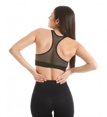 Beyaz arka planda sırt ağrısı çeken genç bir kadın.