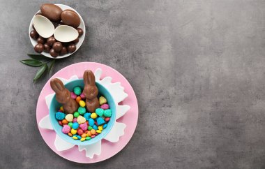 Çikolata Paskalya tavşanları ve gri arka plan üzerinde şekerler kompozisyonu